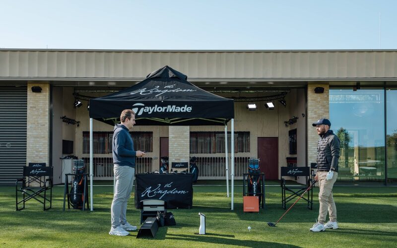 two men stood in front of the golf studio at the grove with a thin sliding door in the background